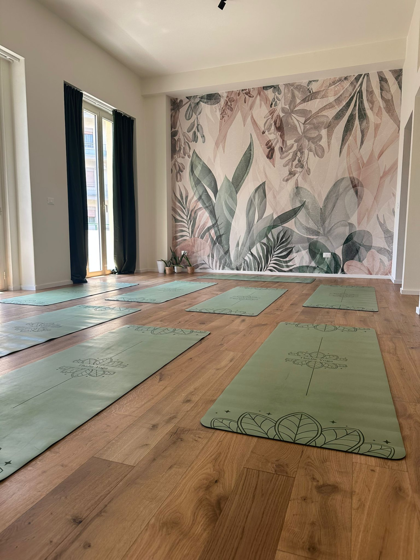 Sala dello studio Thalìa Yoga con tappetini verdi